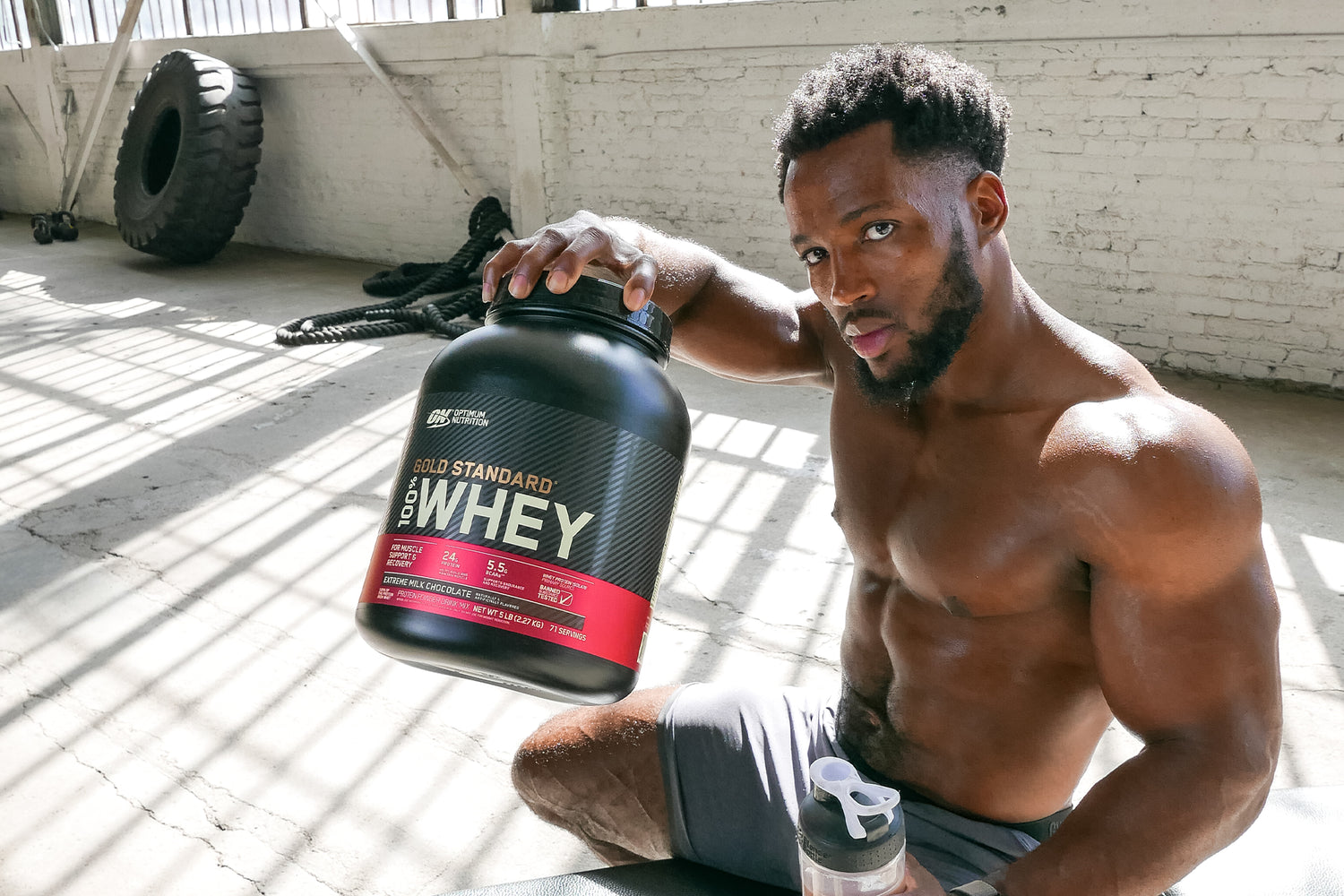 Man Holding Up a Tub of Gold Standard Whey Post-Workout