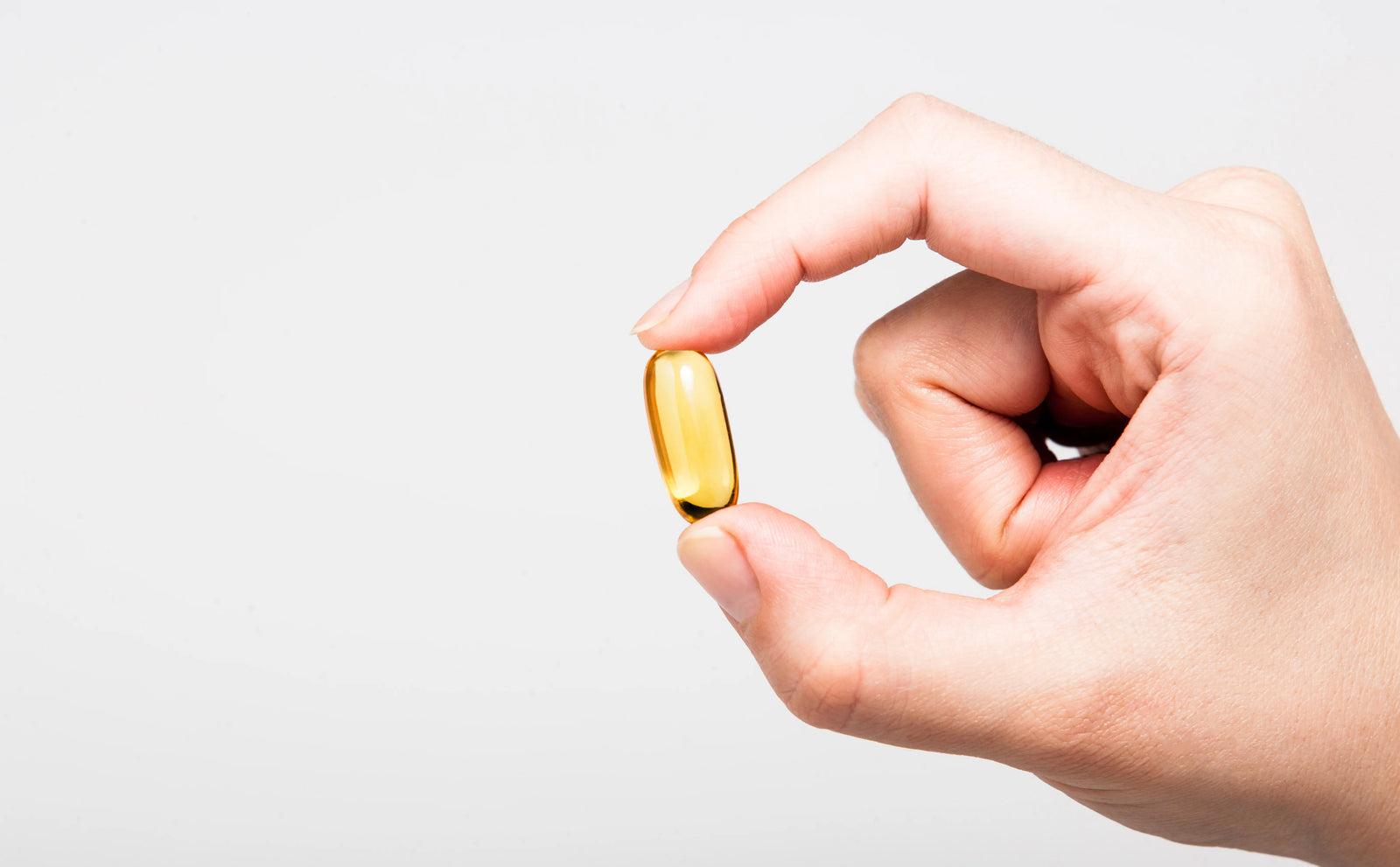 Person holding a fish oil capsule