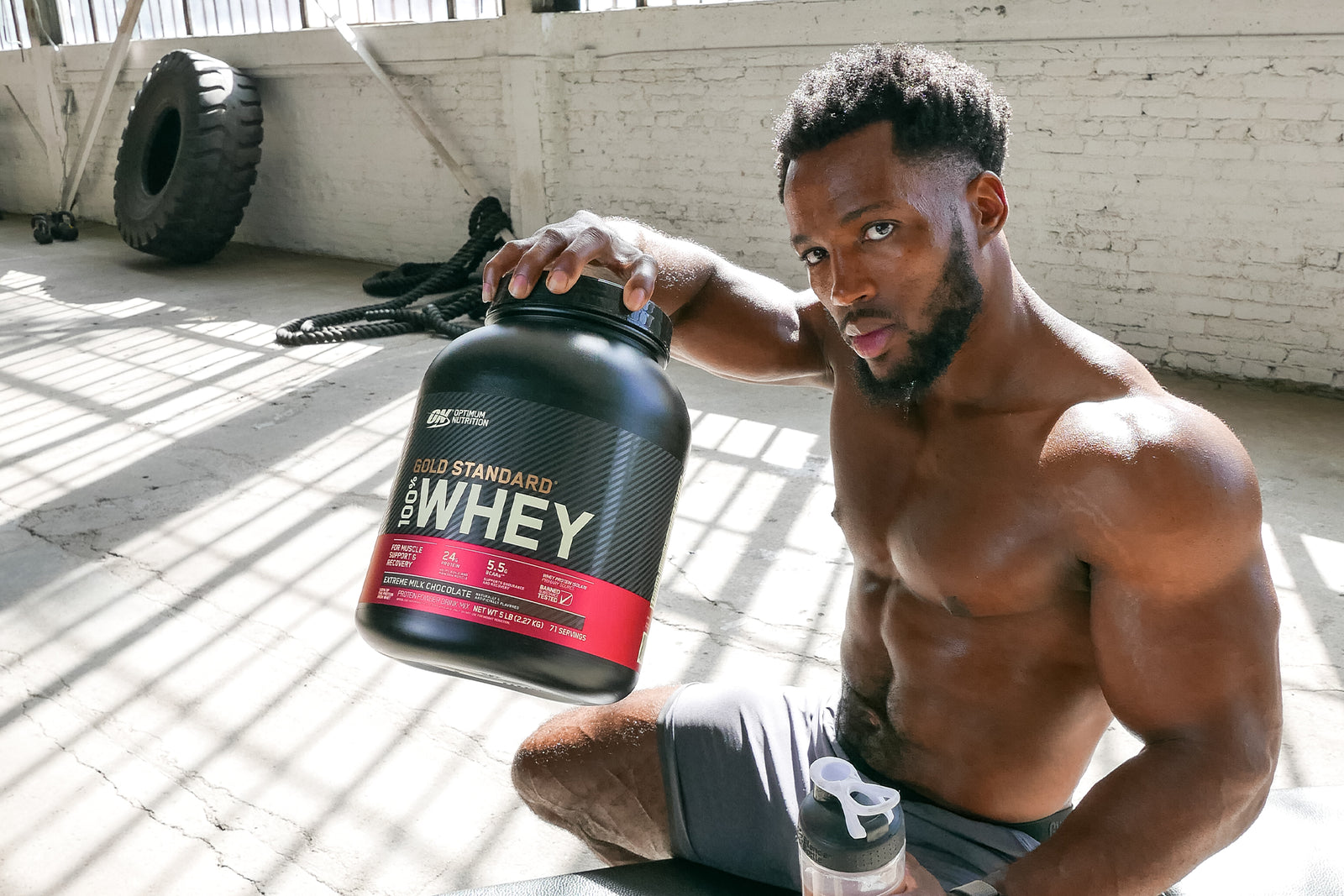 Man Holding Up a Tub of Gold Standard Whey Post-Workout