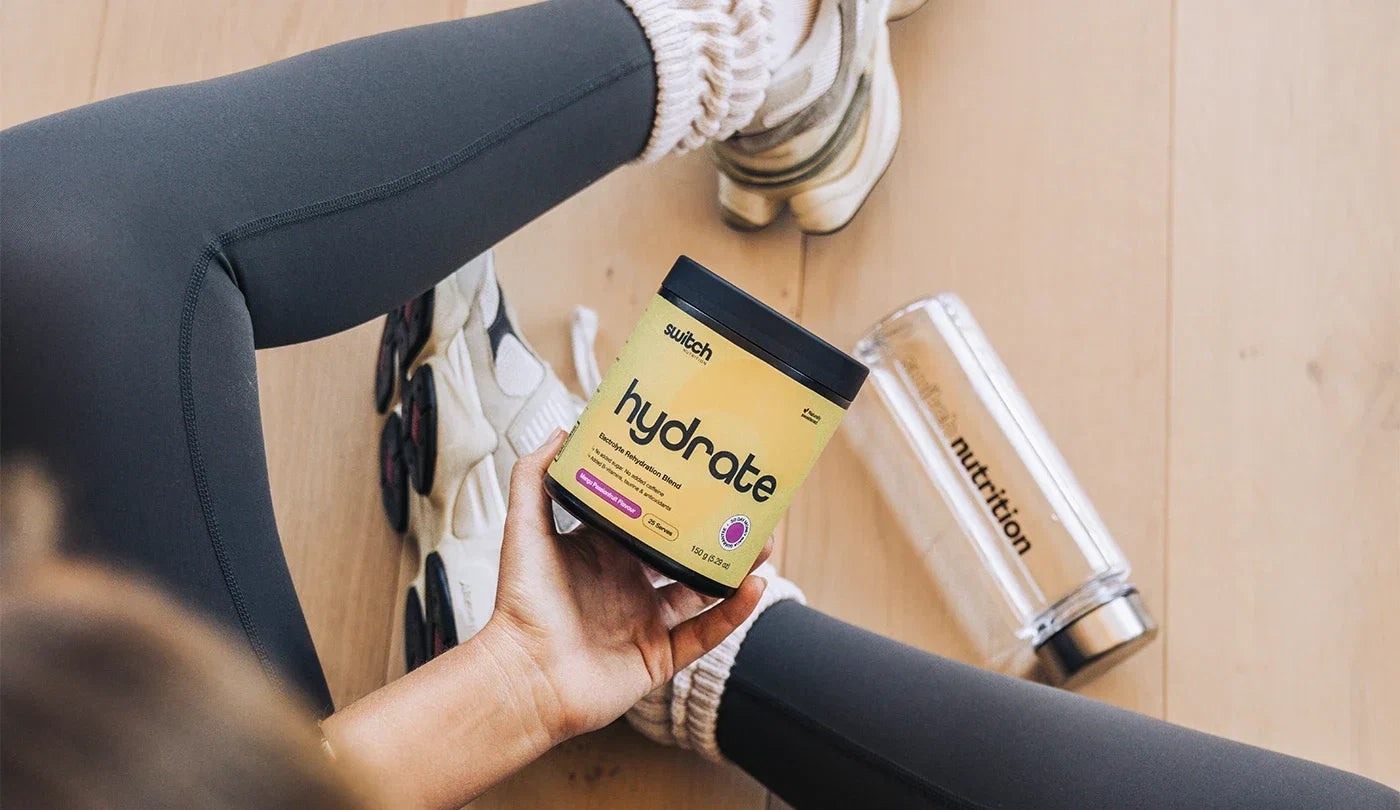 Woman holding a tub of Switch Nutrition Hydrate Electrolytes