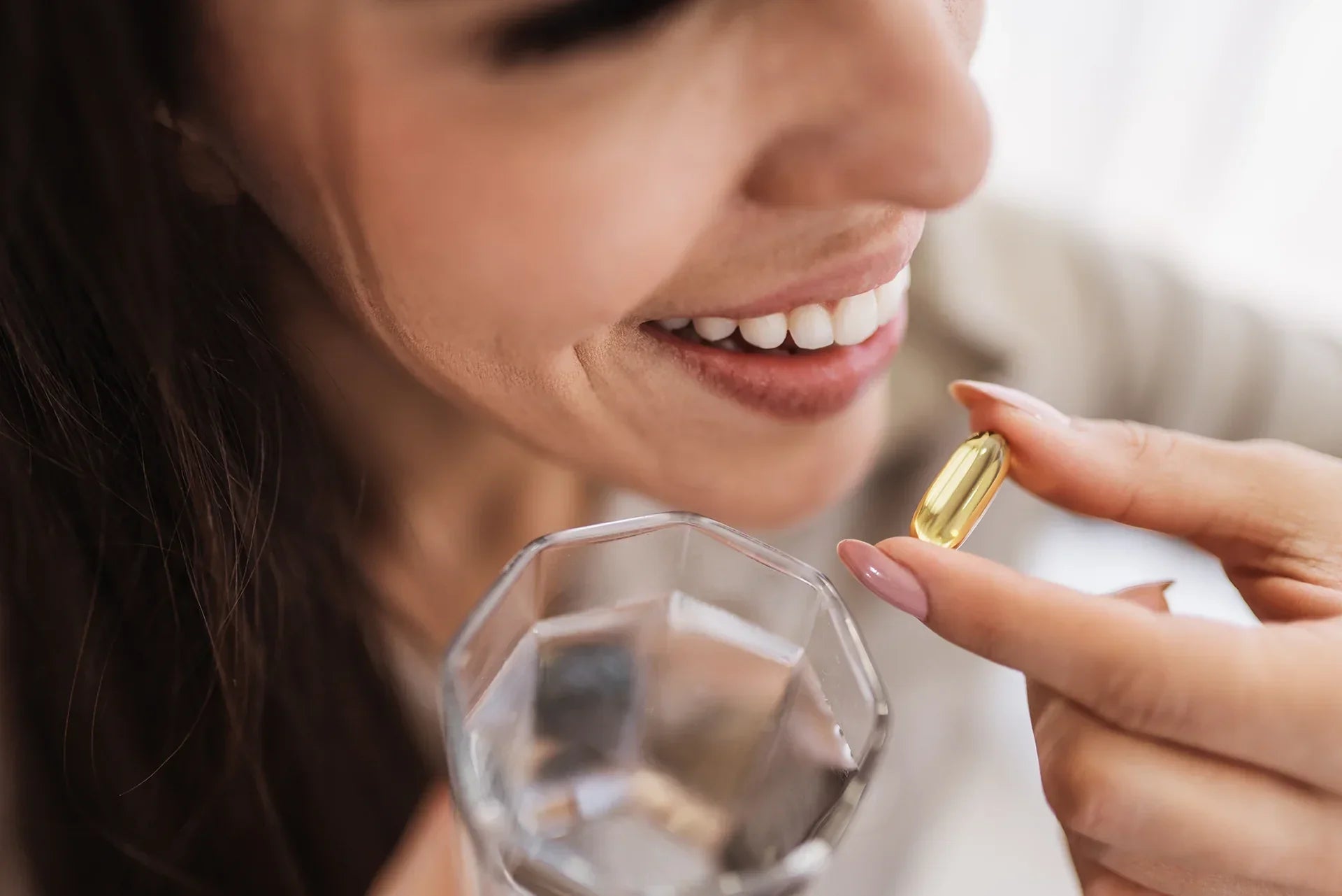 Woman holding a fish oil capsule with a glass of water