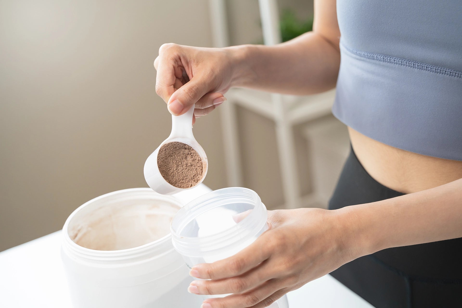 Woman scooping an unbranded protein powder